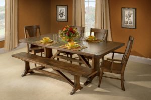 Rustic wood dining table set with centerpiece surrounded by four chairs